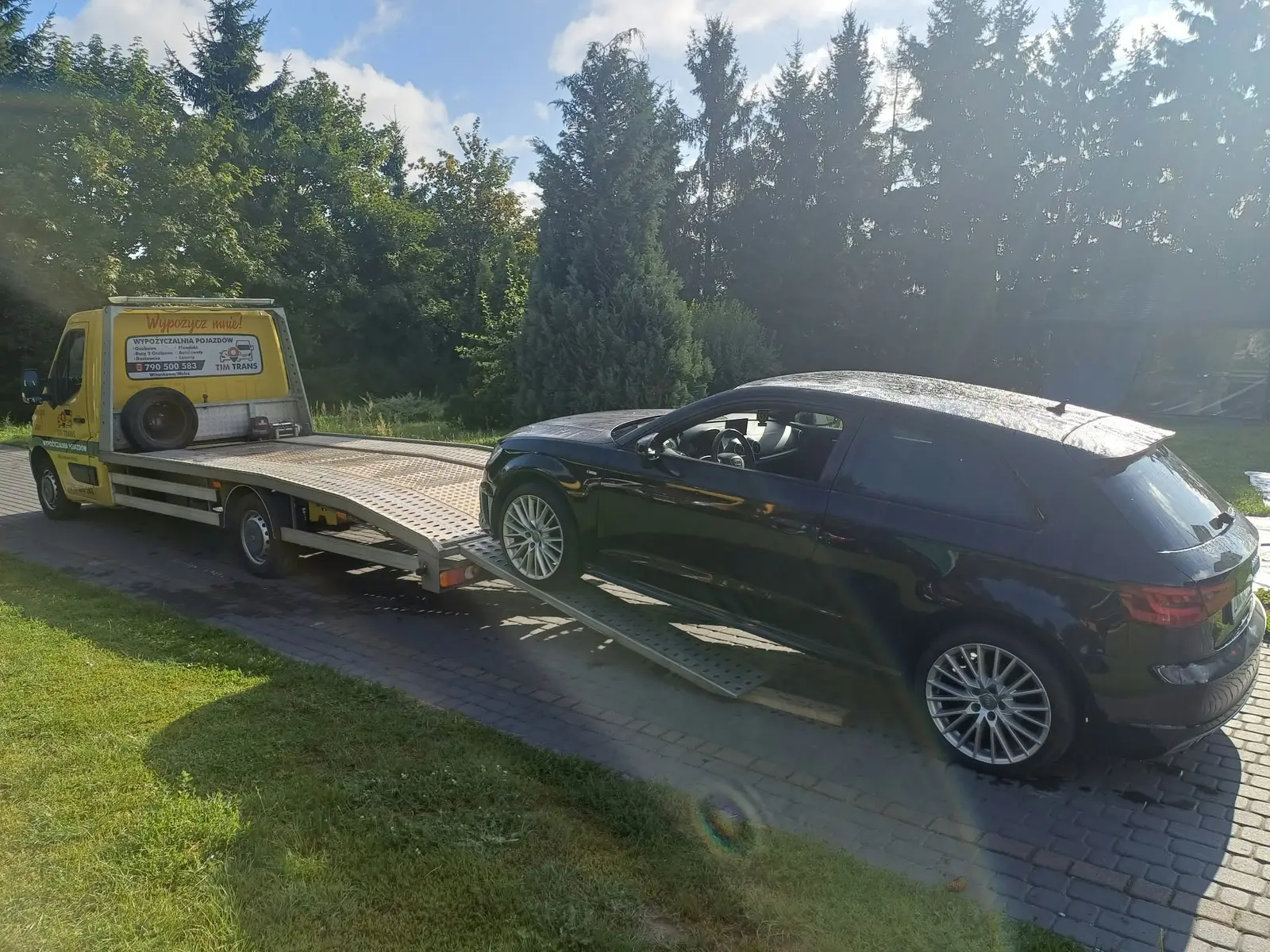 Załadunek czarnego samochodu na żółtą autolawetę Tim Trans